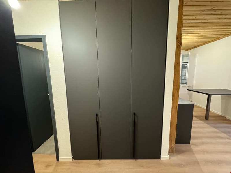 three panel closet, wooden pillar, wooden floor, table, entrance to another room