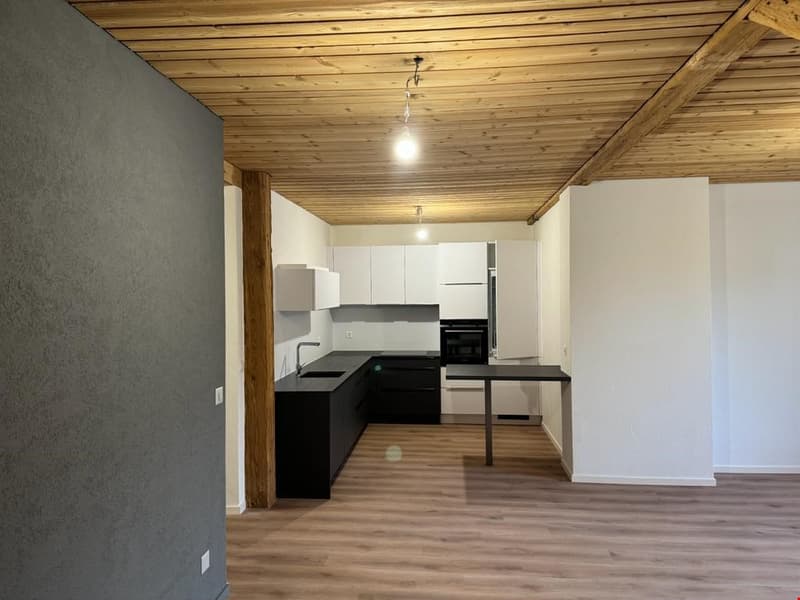 Modern kitchen, white cabinets, wooden ceiling, dark countertops, small worktable, black oven