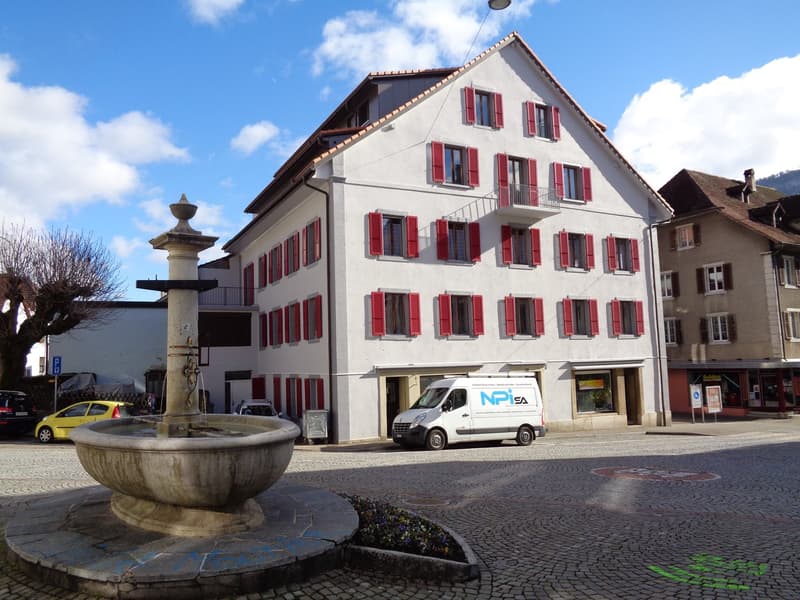 large white building with red shutters, modern windows, fountain in front