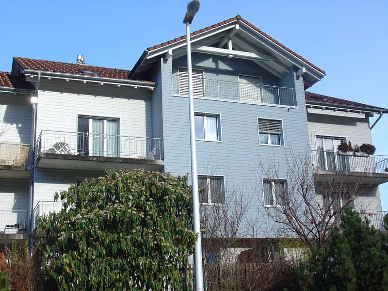 4 story residential building, brick roof, tiled walls, multiple balconies, windows with curtains