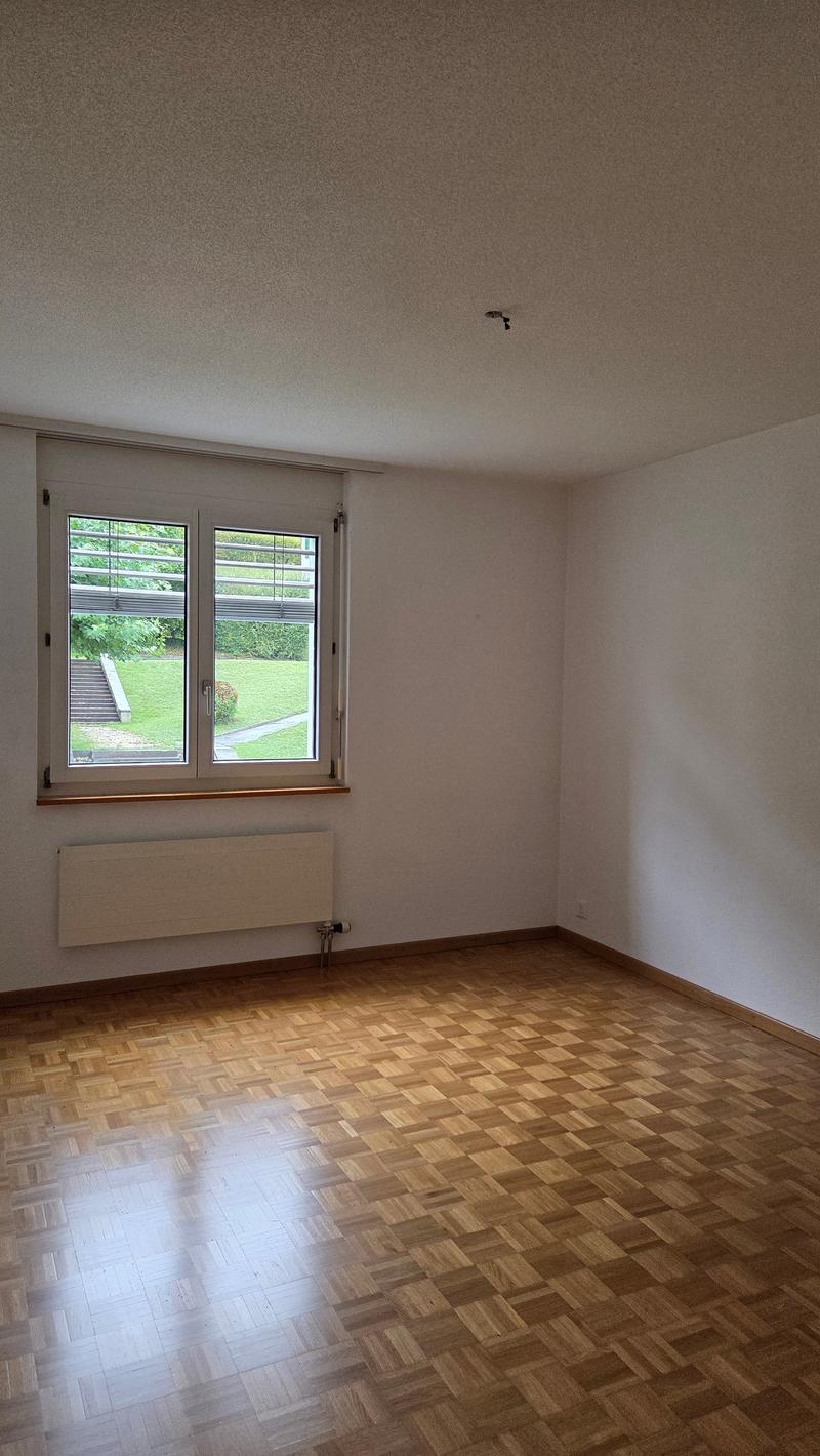 square room, window, radiator, wooden floor, view of garden