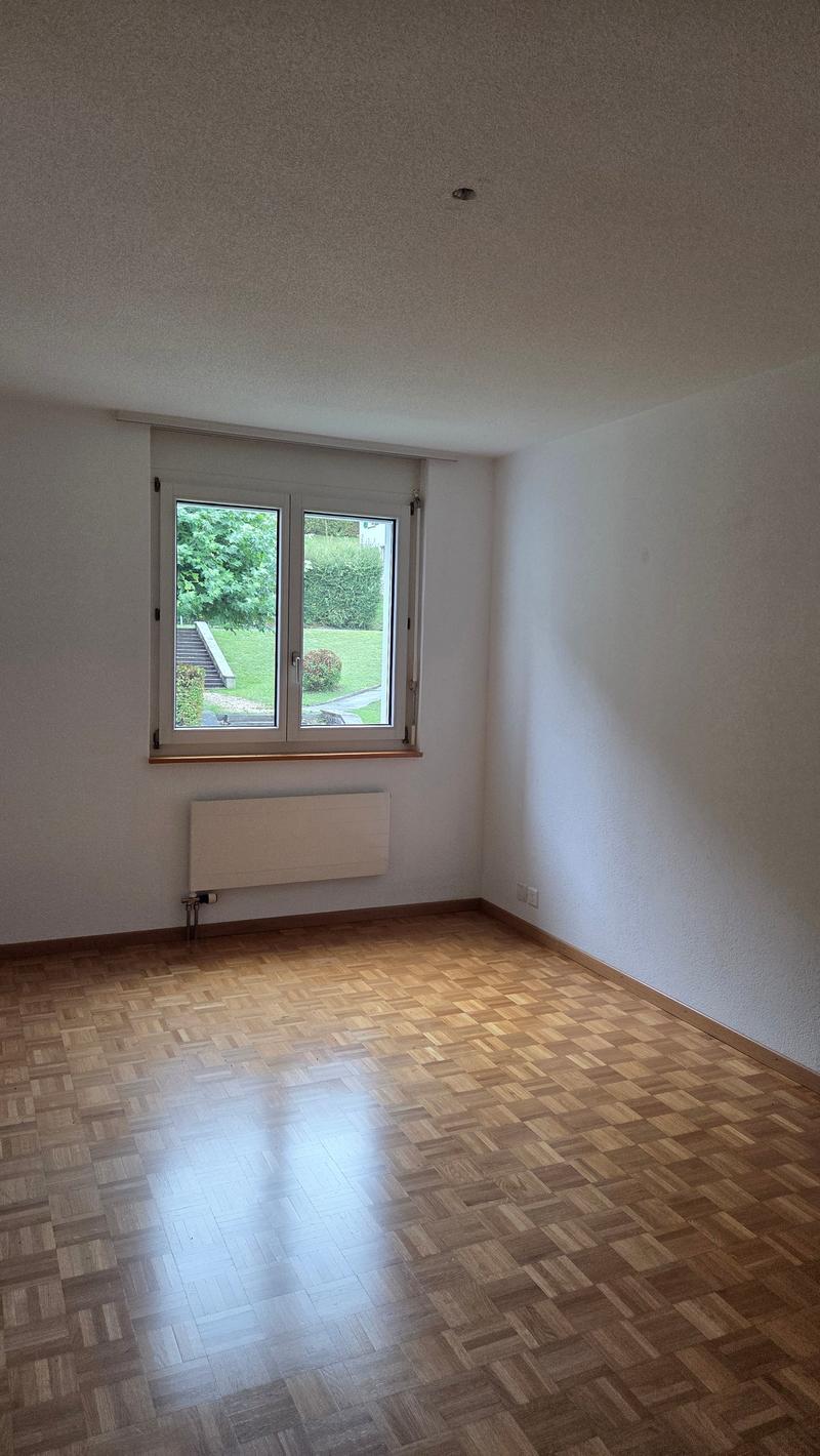 Empty room with windows, wooden floor, heater below window