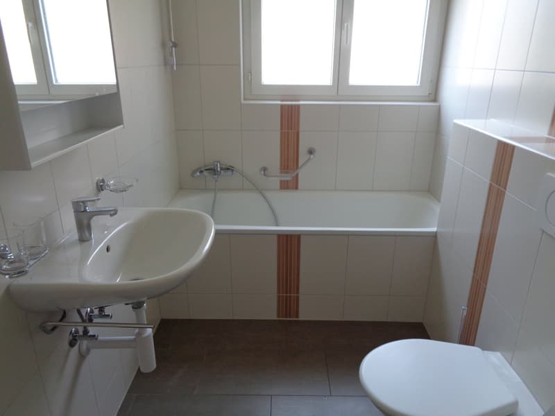 Bathroom with bathtub, sink, toilet, and glass shelves.