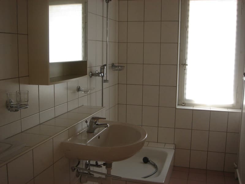 Bathroom with white tiles, sink, mirror, bathtub, shower, and window.