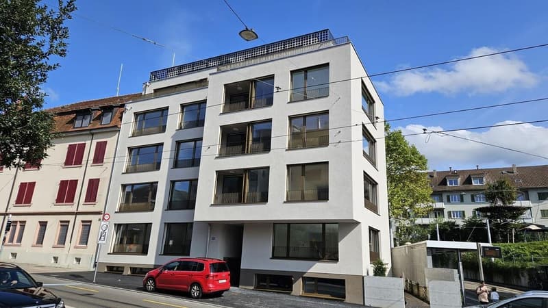 4 story residential building, multiple balconies, red car parked in front