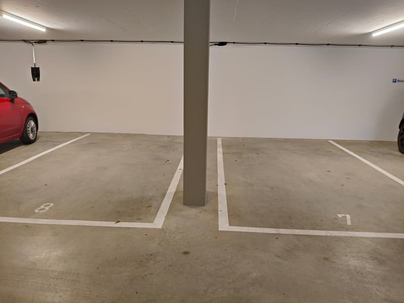 empty underground parking with two parking spaces and one pillar in the middle