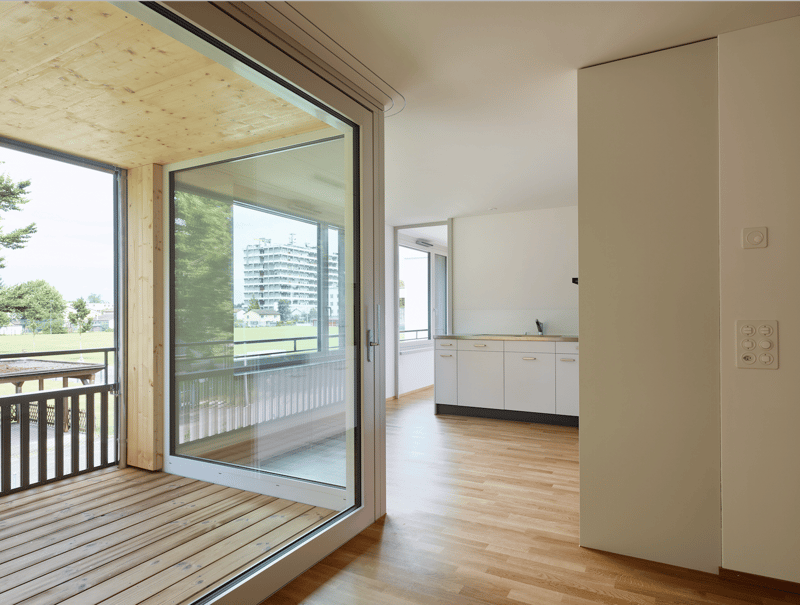 wooden floor, large glass doors, balcony, white kitchen cabinets, white walls