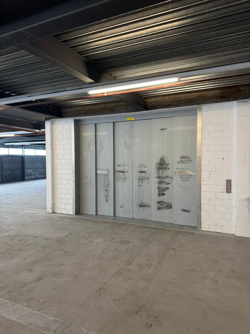 underground parking, silver doors, white brick wall, grey floor