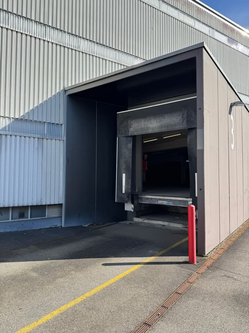 Entrance door to a garage with a lift, paved lot