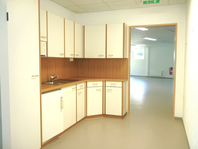 empty kitchen with white cabinets, wooden countertops, sink, faucet, and a door leading to another room