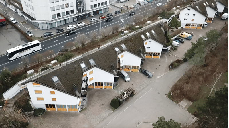 3 residential units with parking spaces in front, ground level, yellow shutters, windows, some grass visible, road with vehicles