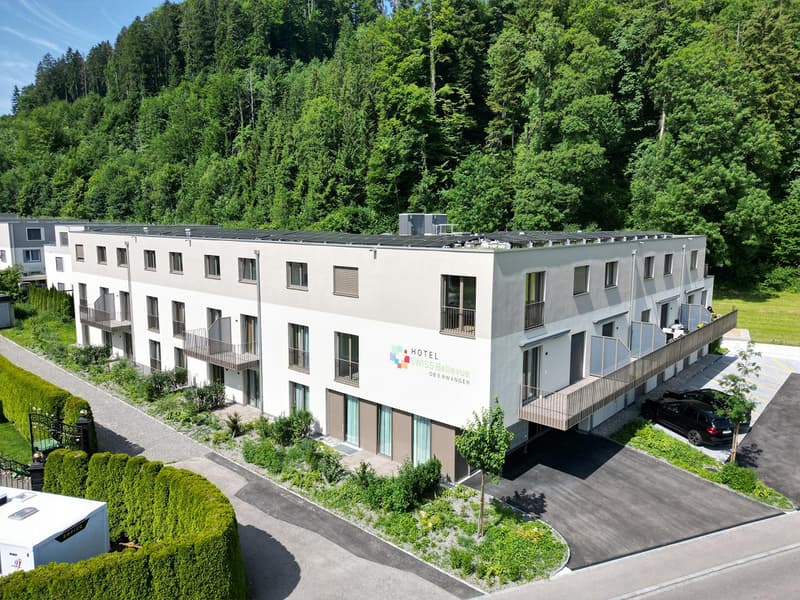 Three-story hotel with solar panels, balconies, and a parking area.