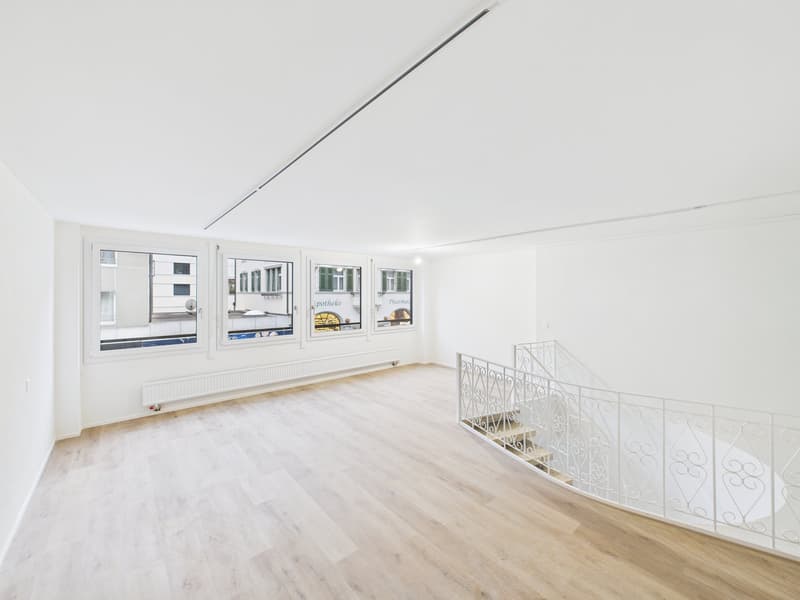 wide empty room, wooden floor, white walls, large windows, spiral staircase