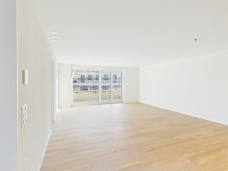 Empty room, wooden floors, sliding glass doors leading to balcony