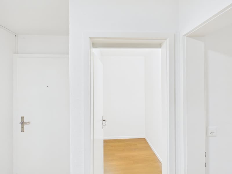 Empty room, wooden floor, white walls, open door