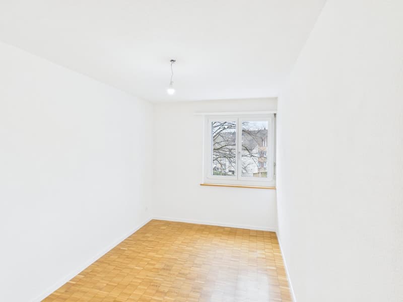 empty room with white walls, wooden floor, single window, and ceiling light
