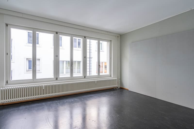 empty room, large windows, white walls, radiator, gray floor
