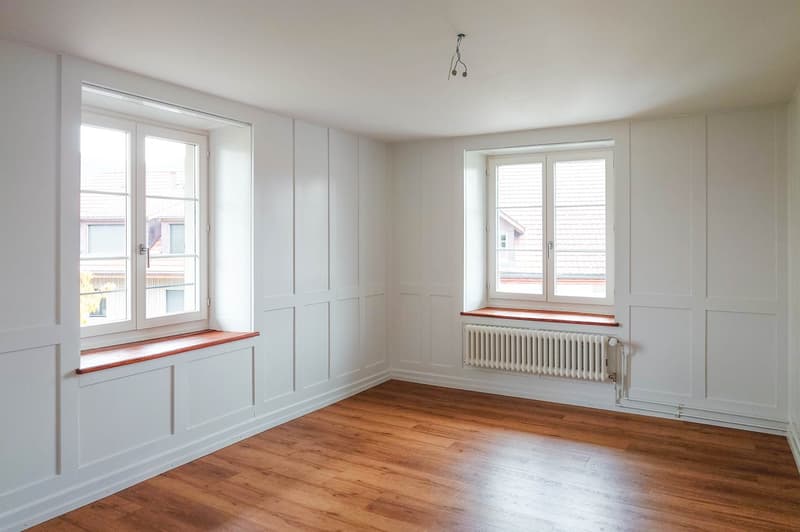 empty room, hardwood floor, white walls, white ceiling, two large windows, white radiator