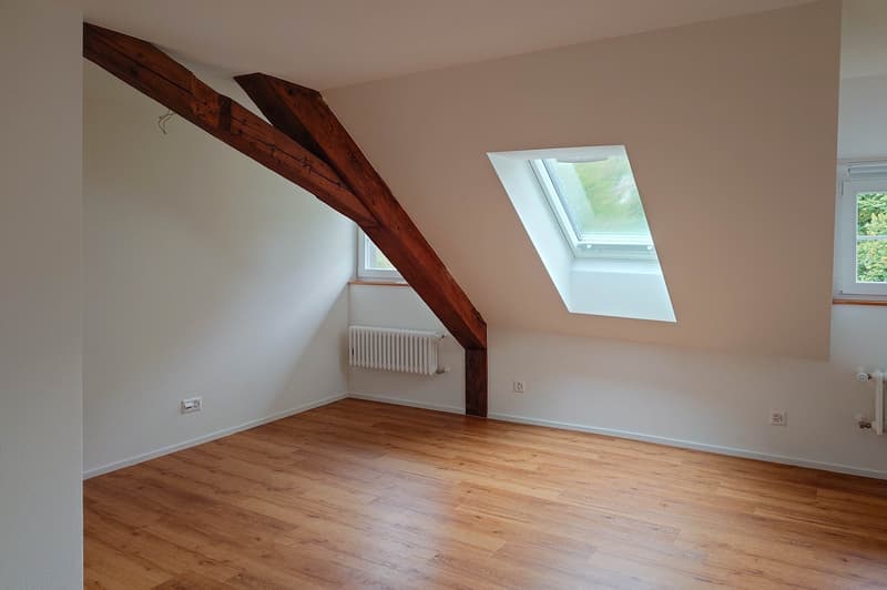 wooden ceiling beams, wooden floor, two windows, white painted walls, two radiators