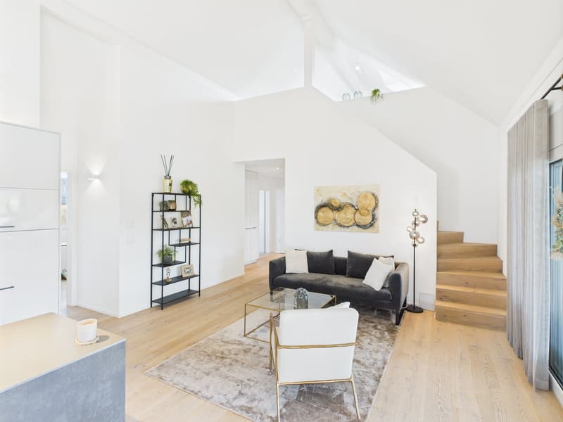 modern living room with white walls, wooden floor, gray sofa, glass coffee table, white armchair, rug, wooden staircase, black shelf with plants, artwork on the wall