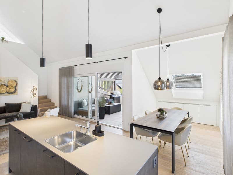 modern kitchen with island, dining area, sliding glass doors to balcony, wooden floors, white walls, pendant lights, open to living area