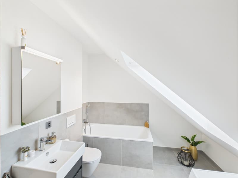 modern bathroom, white walls, gray tiles, bathtub, toilet, sink, mirror, plants