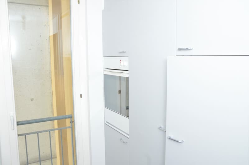 Balcony door, white kitchen cabinets, stainless steel refrigerator, dishwasher, oven