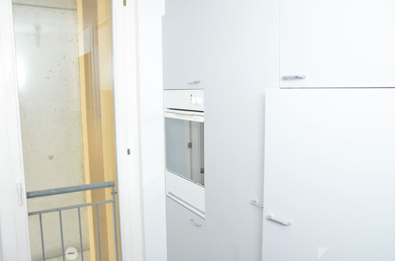 Balcony door, white kitchen cabinets, stainless steel refrigerator, dishwasher, oven