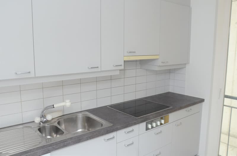 White cabinets, granite countertop, stainless steel sink, built-in oven, gas stove, and a window