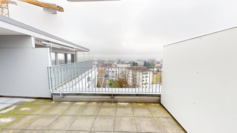 balcony with railing, concrete floor, buildings in distance