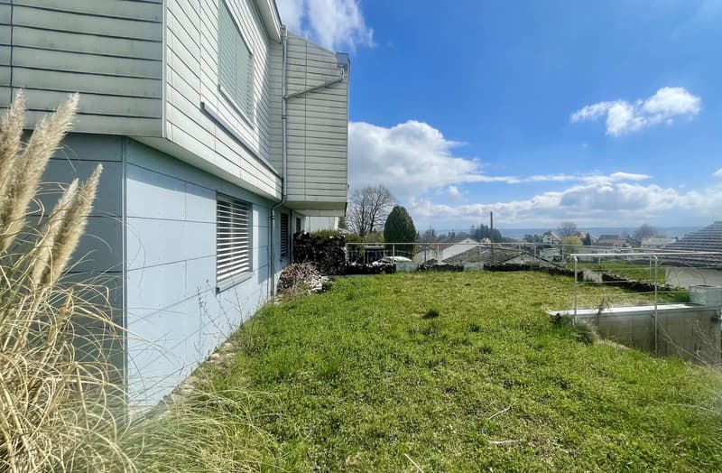Modern house with raised ground floor, grassy yard, and outdoor storage area.
