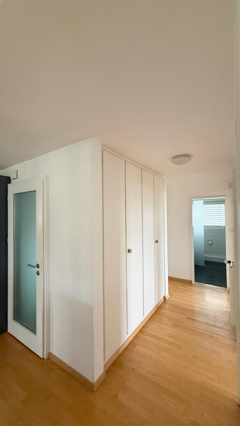 Wooden floor, white walls, white door, large closets, bright light from the entrance