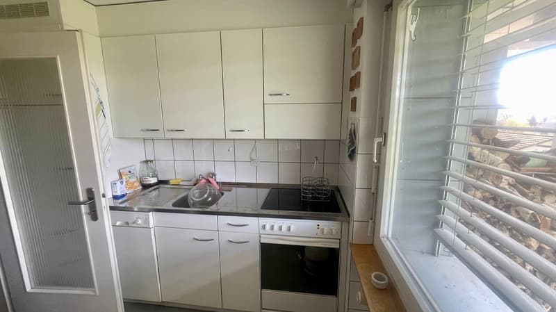 white cabinets, tiled backsplash, gas stove, electric oven, sink, dishwasher, washing machine, large window with blinds