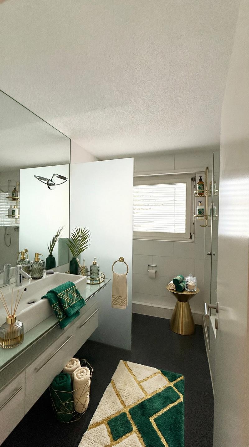 bathroom with large mirror, white vanity with double sink, towels, green rug on floor