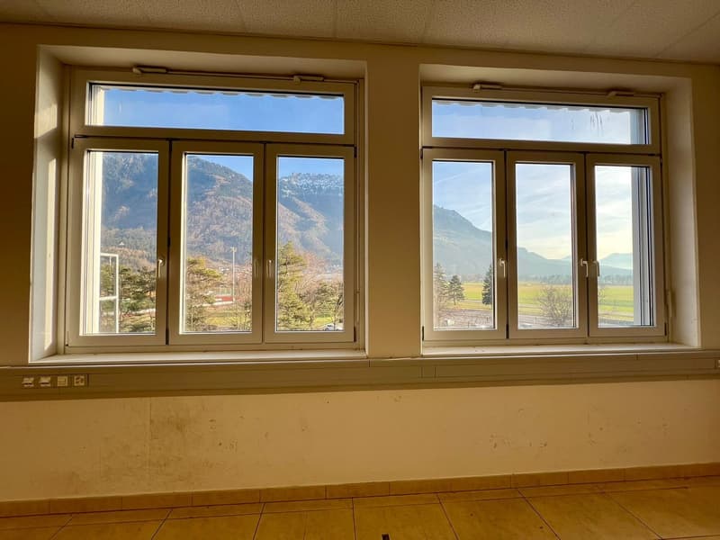 Large windows with a scenic mountain view, hardwood floor, beige walls
