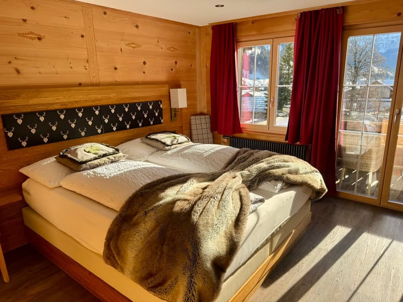 wooden walls, two beds, pillows, blankets, lamp, radiator, glass doors, window, curtains