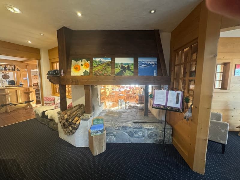 wooden beam fireplace, picture frames above fireplace, small seating area, magazines on table