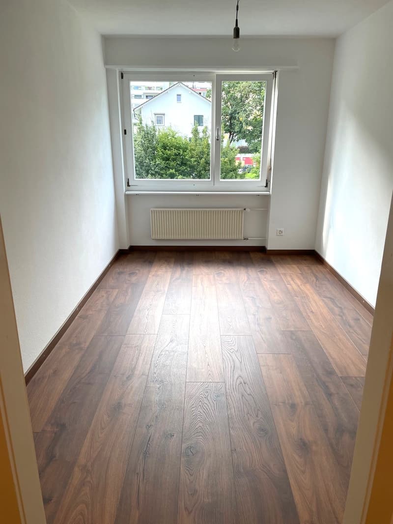 empty room, wooden floor, white walls, large window, white radiator