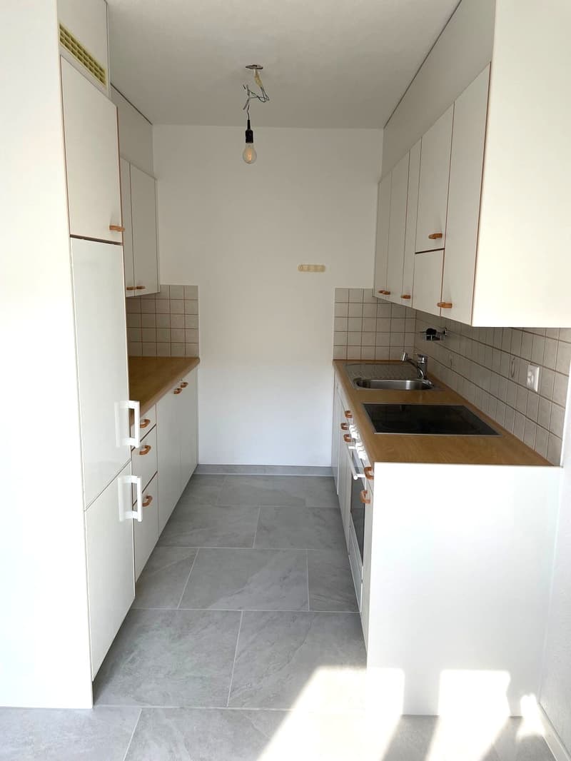 modern kitchen with white cabinets, wooden countertops, stainless steel sink, gas stove, and tiled floor