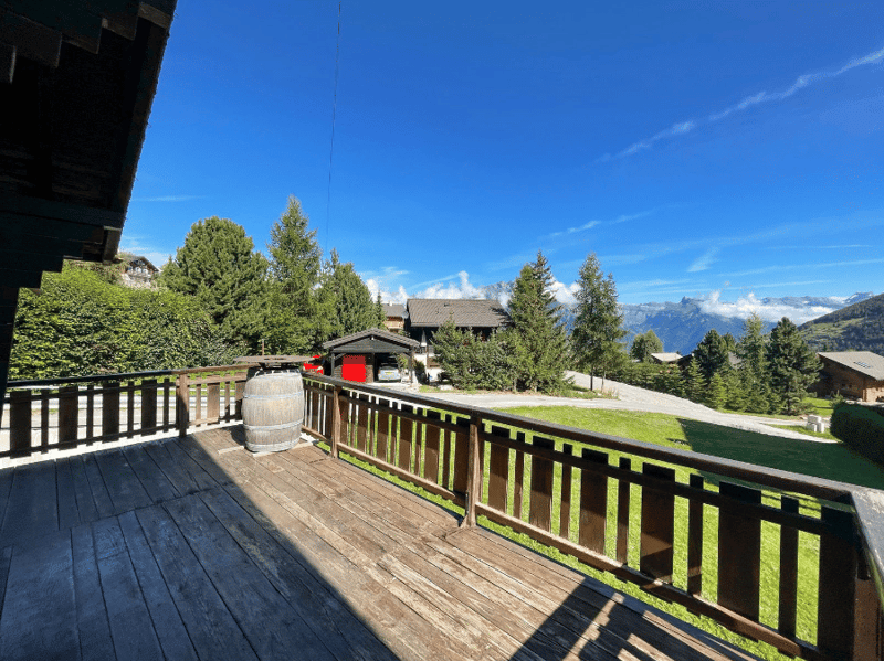 wooden deck, wooden railing, barrel, green grass, trees, mountains