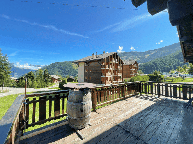 wooden deck, wooden railing, barrel, round table, mountain view