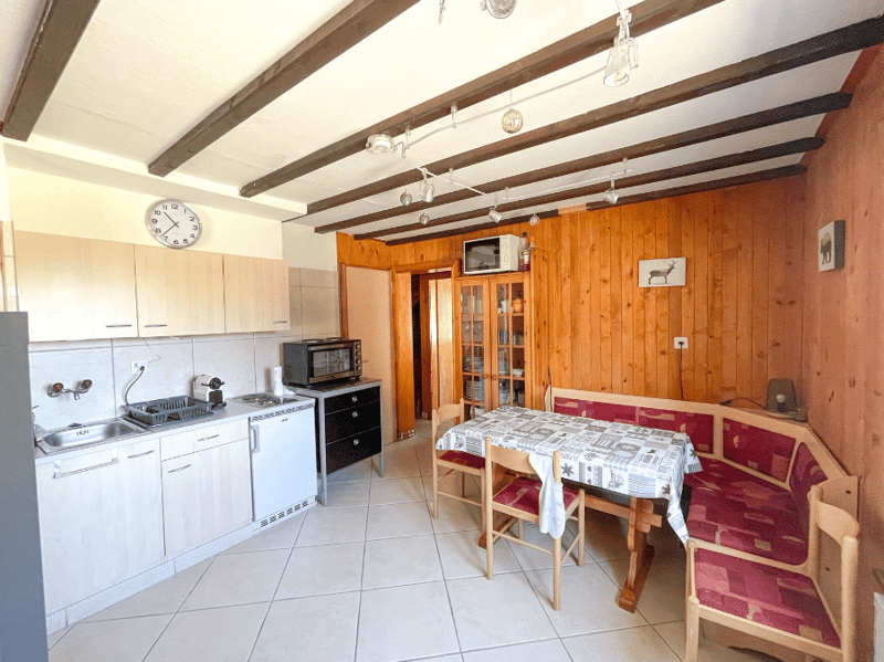 kitchen with dining area, wooden walls, white tiled floor, kitchen appliances, dining table, chairs, microwave, sink, cabinets, power outlets