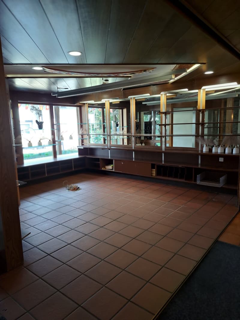 Large open kitchen space with tile flooring, wooden shelving units, and a dishwasher visible.