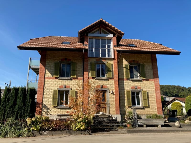 2 story house, brick wall, red tiles, multiple windows, small garden, steps in front