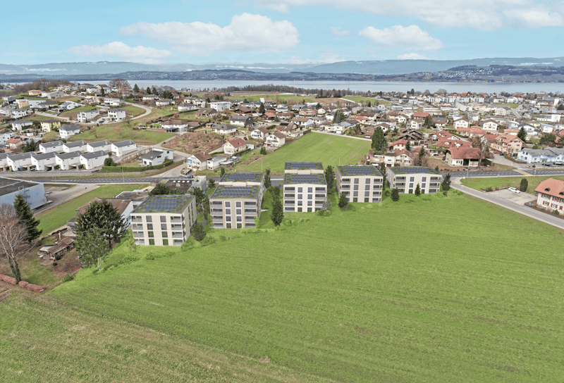 The image shows a residential area with a mix of apartment buildings and single-family homes. The buildings have solar panels installed on the roofs, indicating the use of renewable energy. There are green spaces and roads visible, as well as a view of th