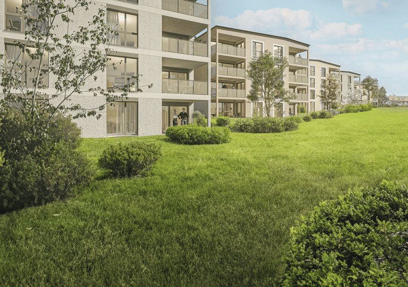 Multi-story apartment building with balconies, surrounded by lush green lawn and landscaping