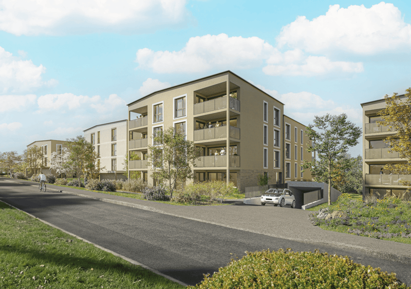 3-story apartment building with balconies, surrounded by landscaping and a paved driveway with parking spaces
