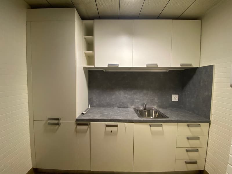 Modern kitchen with white cabinets, gray countertop, stainless steel sink, and built-in dishwasher