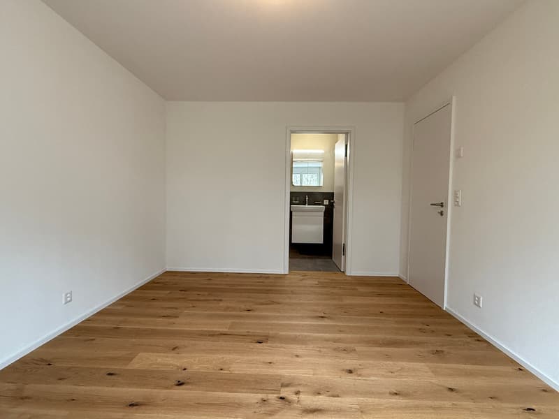 empty room, wooden floor, white walls, two doors, one leading to a bathroom