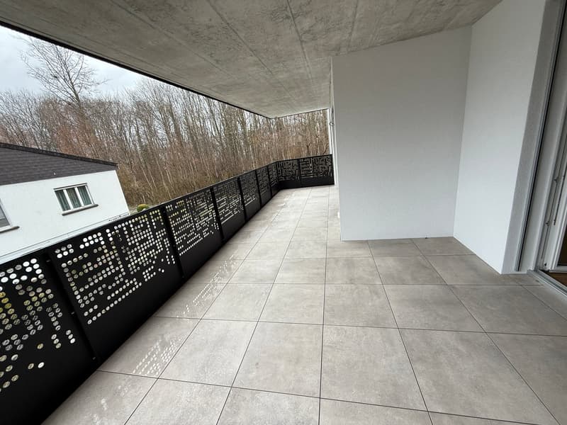 Balcony with tiled floor, black railings, and a view of trees